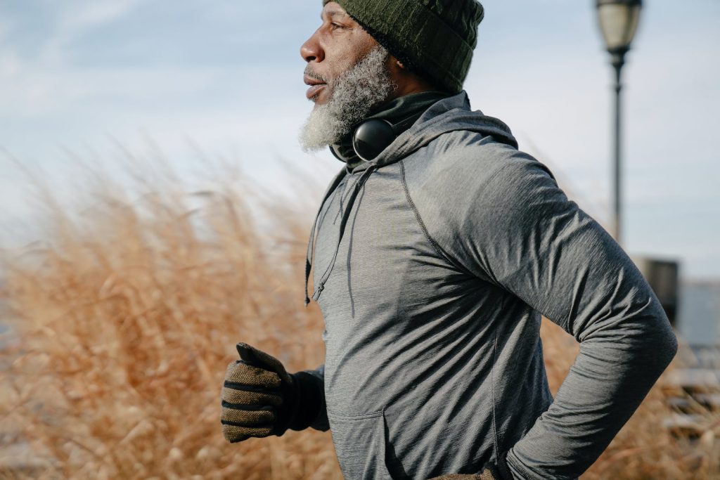 Black man in sportswear jogging in sunny autumn day